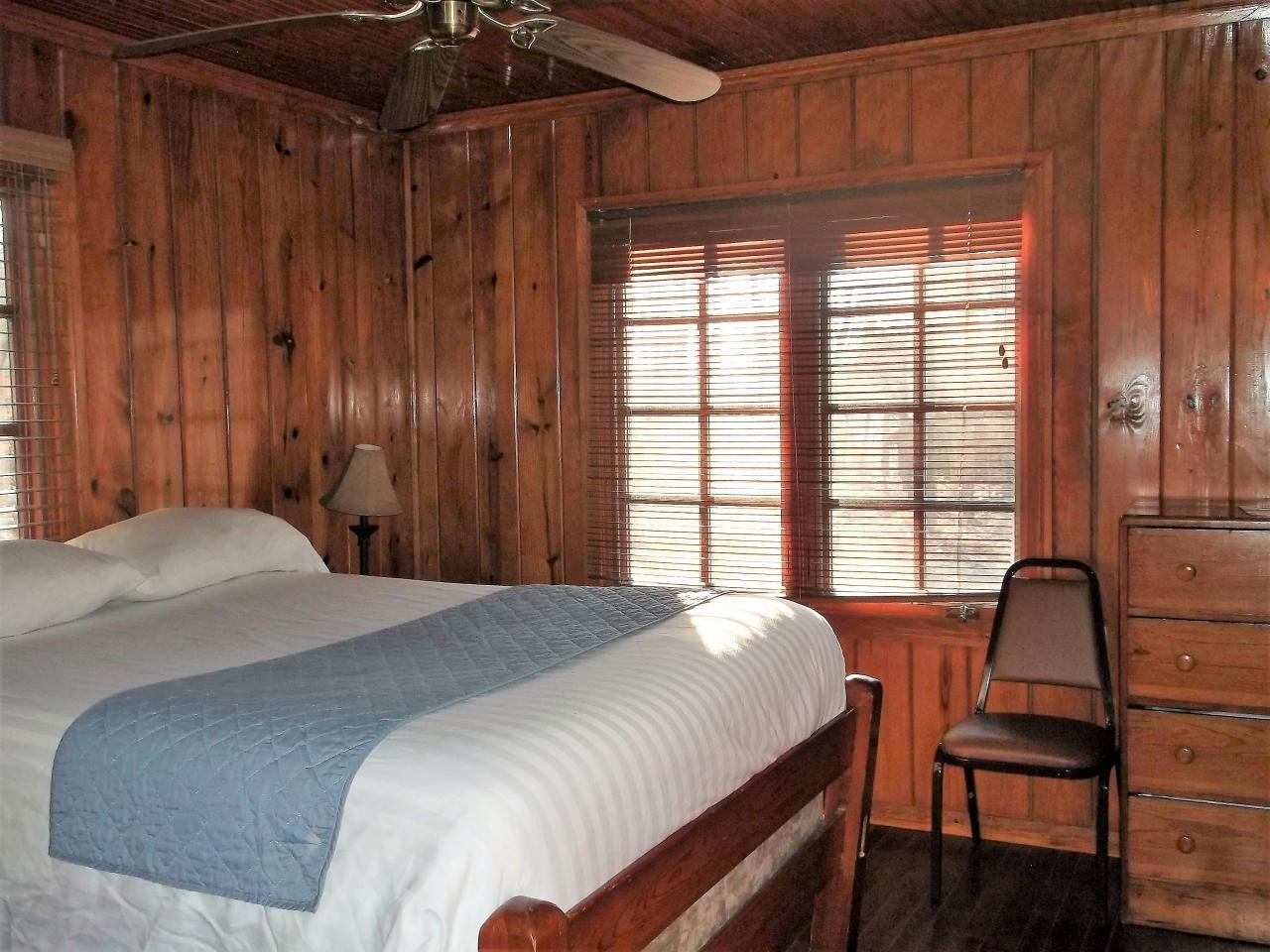 View of one of the bedrooms with bed, dressers and exterior windows